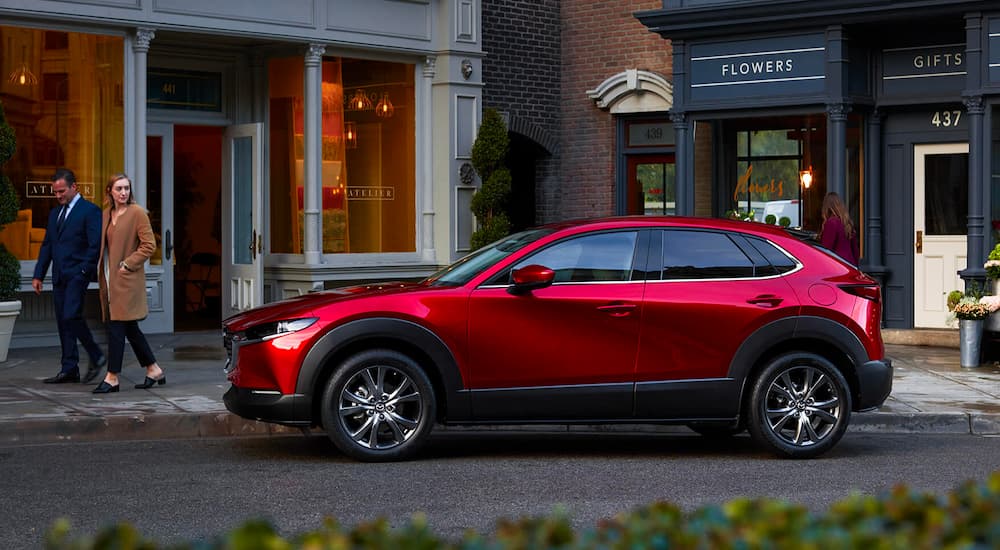 A red 2023 Mazda CX-30 is shown parked near some shoppes after visiting a Mazda dealer.