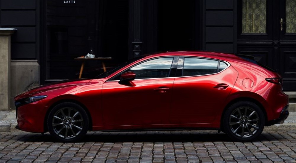 A red 2023 Mazda 3 is shown parked near a building.