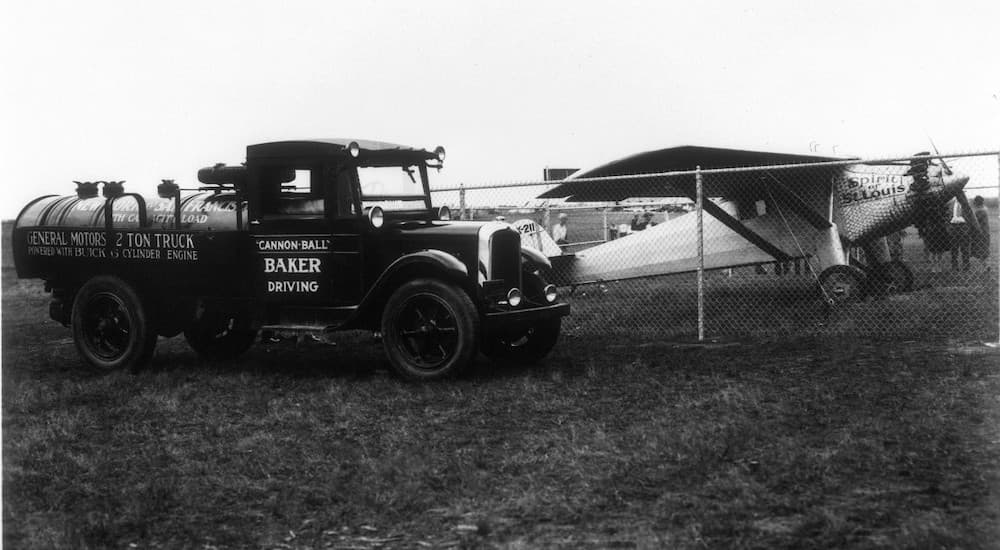 A 1927 GMC Two-Ton Tanker is shown parked near an airplane. 