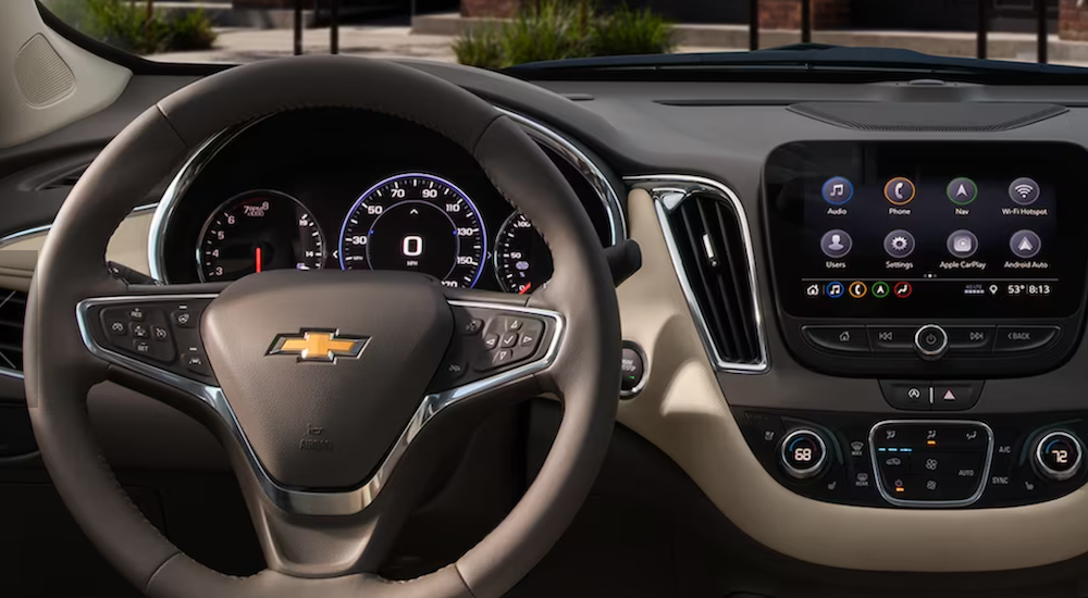 The brown interior of a 2024 Chevy Malibu is shown, including the wheel and dashboard.