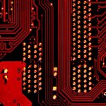 A close-up of a red-and-black computer board is shown.