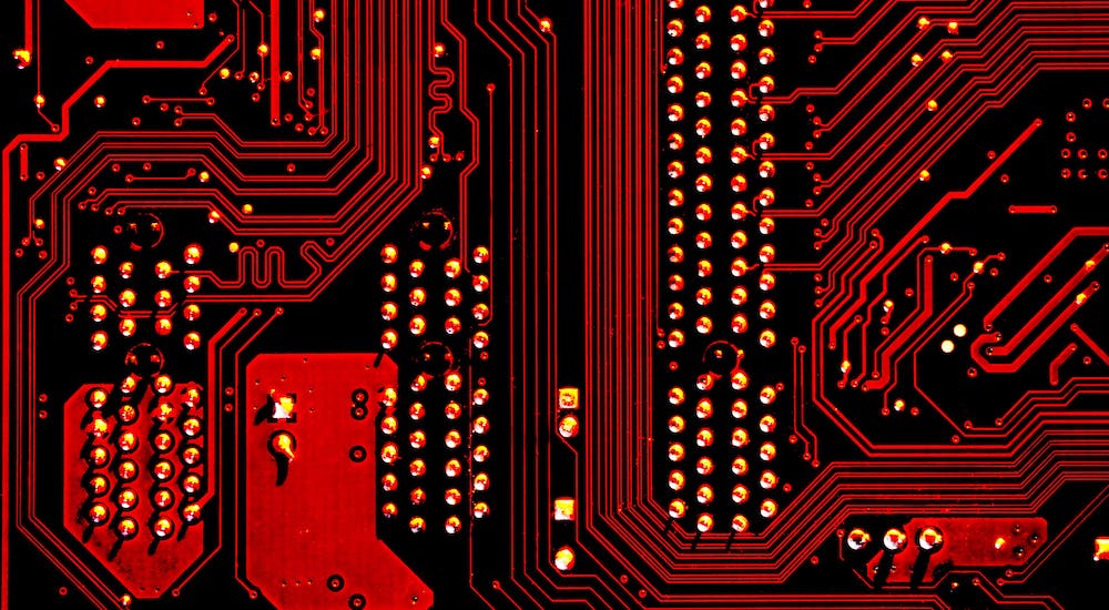 A close-up of a red-and-black computer board is shown.