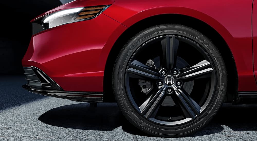 A close up of the front tire on a red 2023 Honda Accord Sport Hybrid-L is shown at a tire shop.