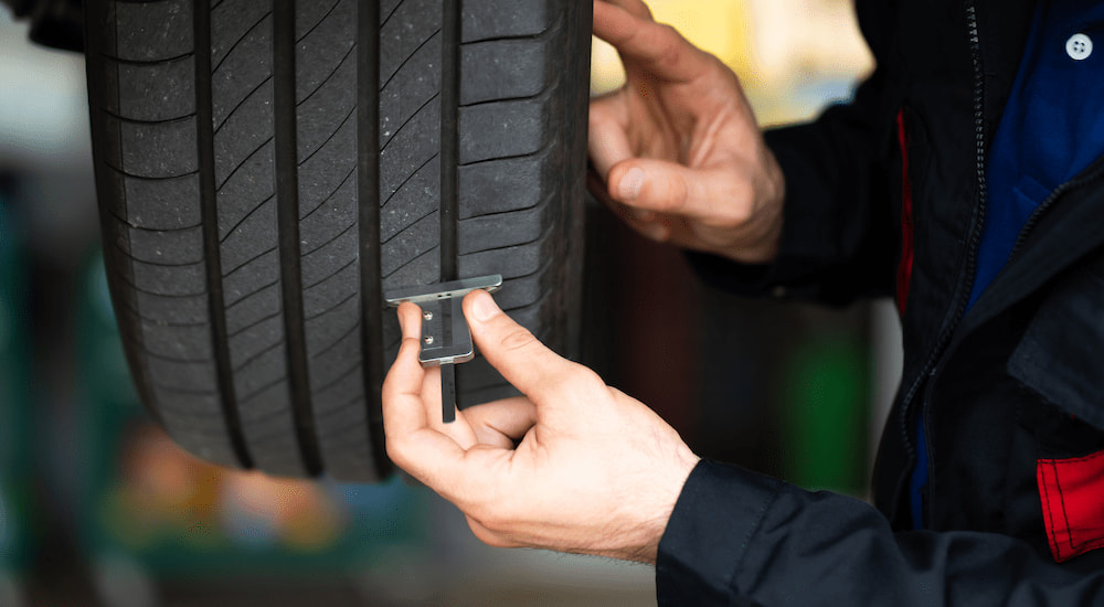 A mechanic is shown checking the tread on a vehicle's tire.