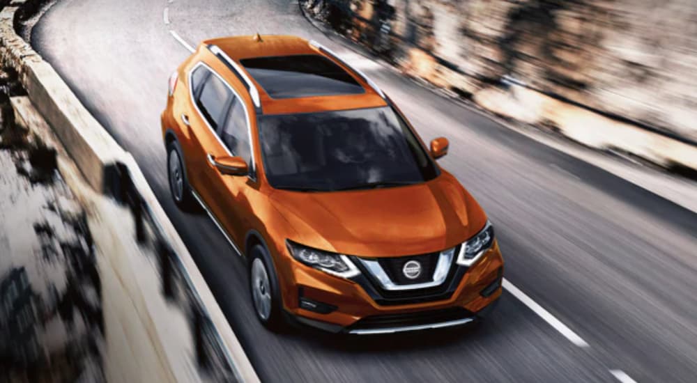 An orange 2020 Nissan Rogue is shown driving on a highway.