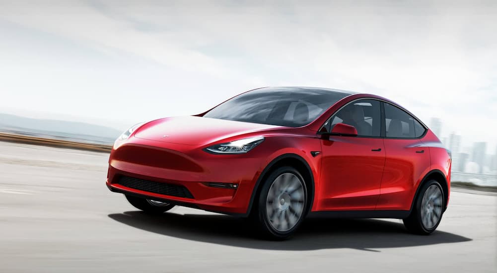 One of the safest cars for sale, a red 2021 Tesla Model Y is shown driving down a road.