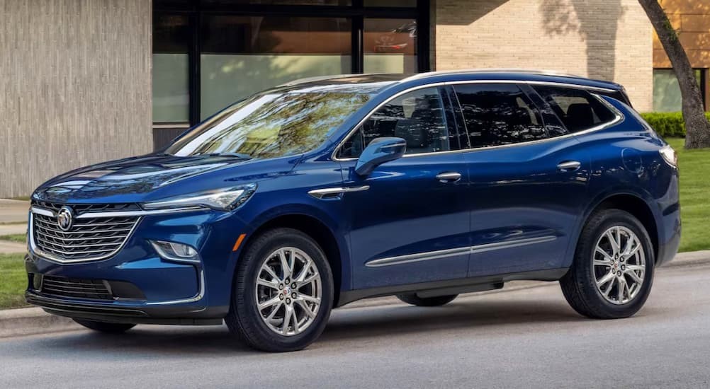 A blue 2023 Buick enclave is shown parked near a curb.