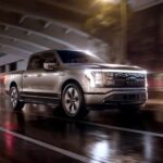 A new Ford F-150 for sale, a silver 2023 Ford F-150 Lightning, is shown driving through a tunnel.