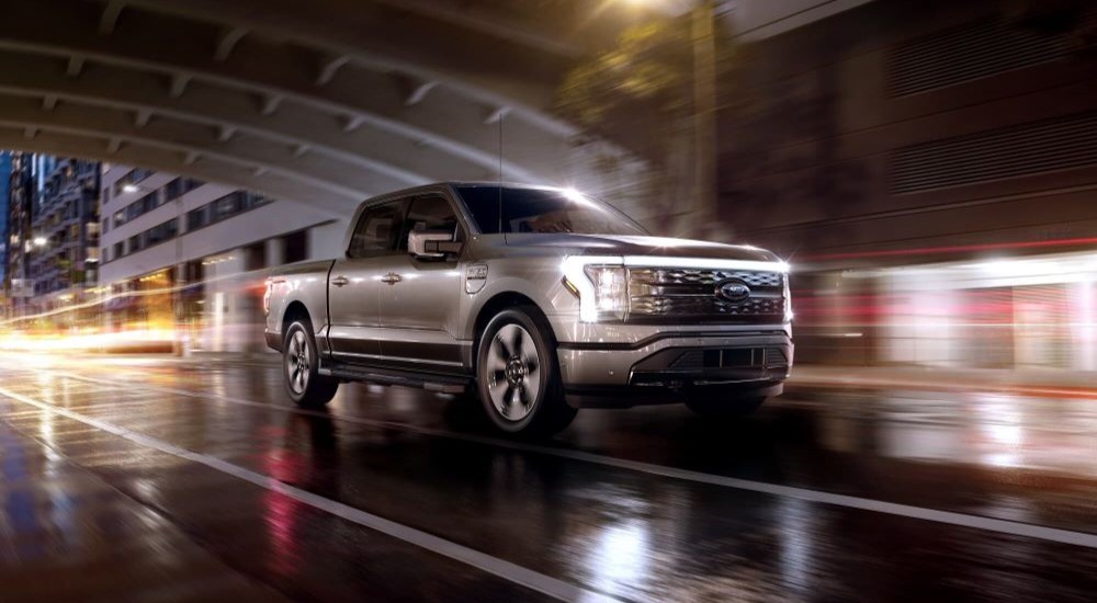 A new Ford F-150 for sale, a silver 2023 Ford F-150 Lightning, is shown driving through a tunnel.