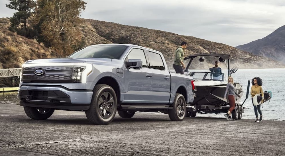 A gray 2023 Ford F-150 Lightning is shown towing a boat.