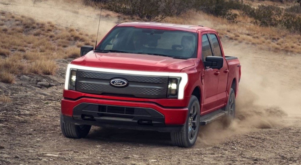 A red 2023 Ford F-150 Lightning is shown driving off-road.