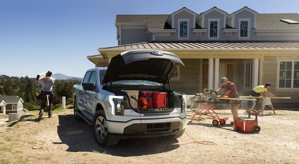 A silver 2023 Ford F-150 Lightning is shown parked on a construction site.