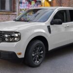 A white 2023 Ford Maverick Lariat is shown parked in a garage.