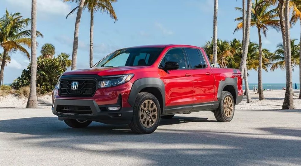 A red 2023 Honda Ridgeline HPD is shown parked near a beach.