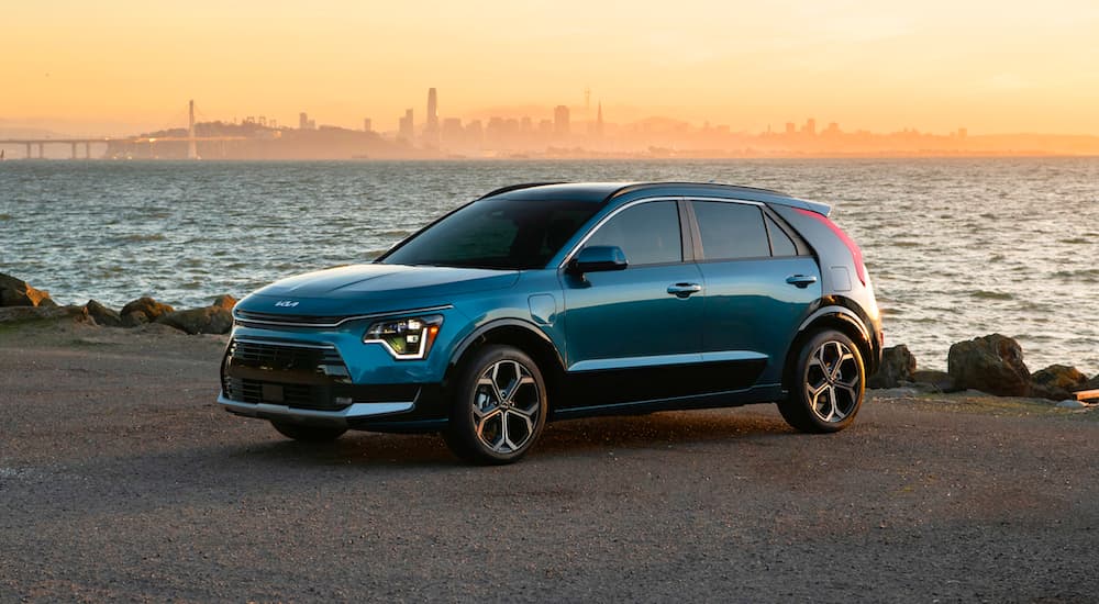 A blue 2023 Kia Niro PHEV is shown parked near a beach.