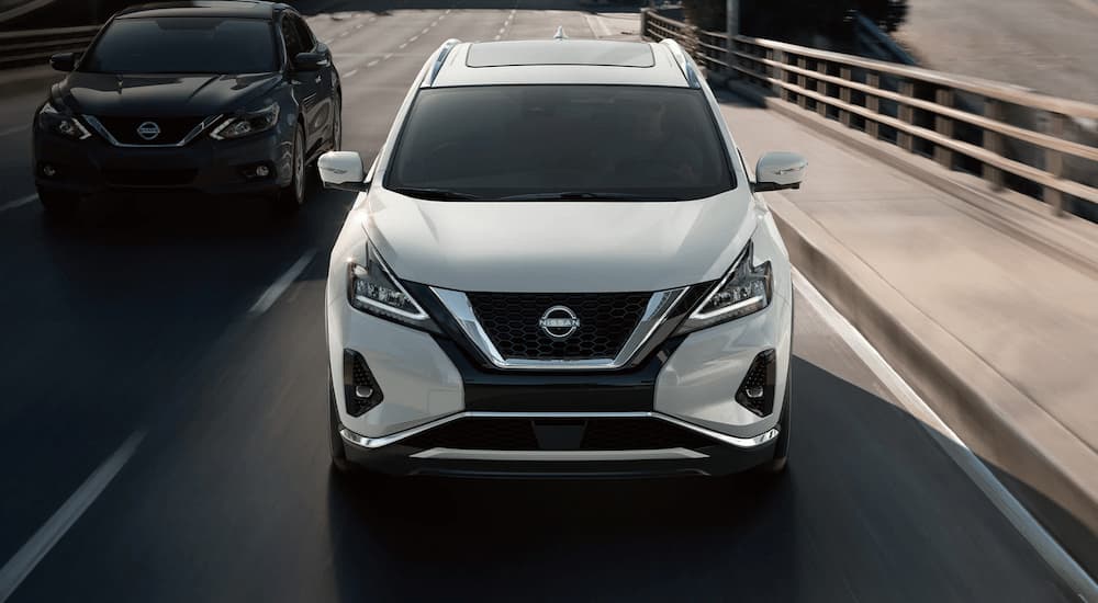 A white 2023 Nissan Murano is shown from the front driving down a highway.
