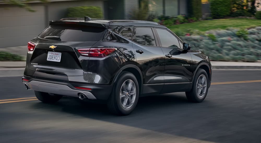 A black 2024 Chevy Blazer is shown from the rear driving on a road.