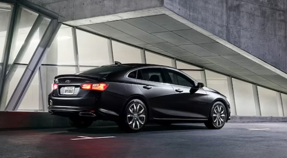 A black 2024 Chevy Malibu Midnight Edition is shown parked near a building.