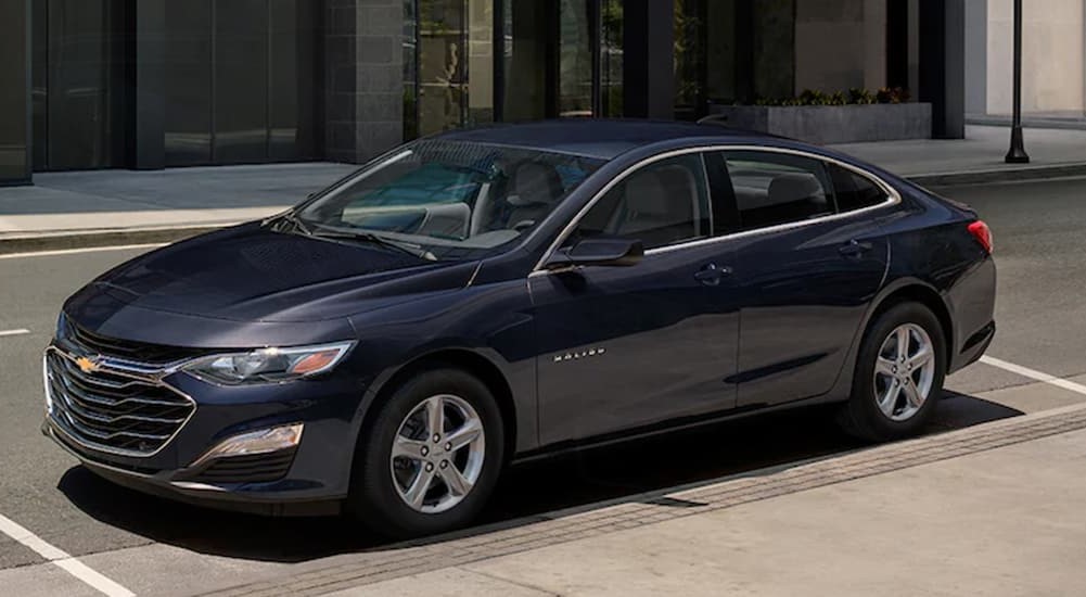 A blue 2024 Chevy Malibu is shown parked on a city street.