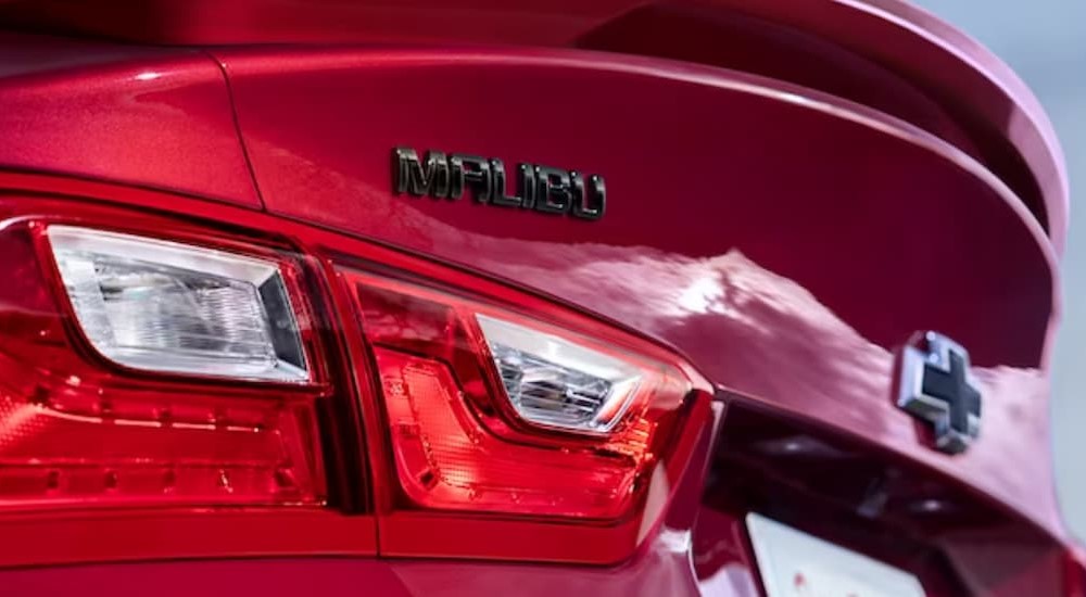 A close-up of the rear end of a red 2024 Chevy Malibu is shown.