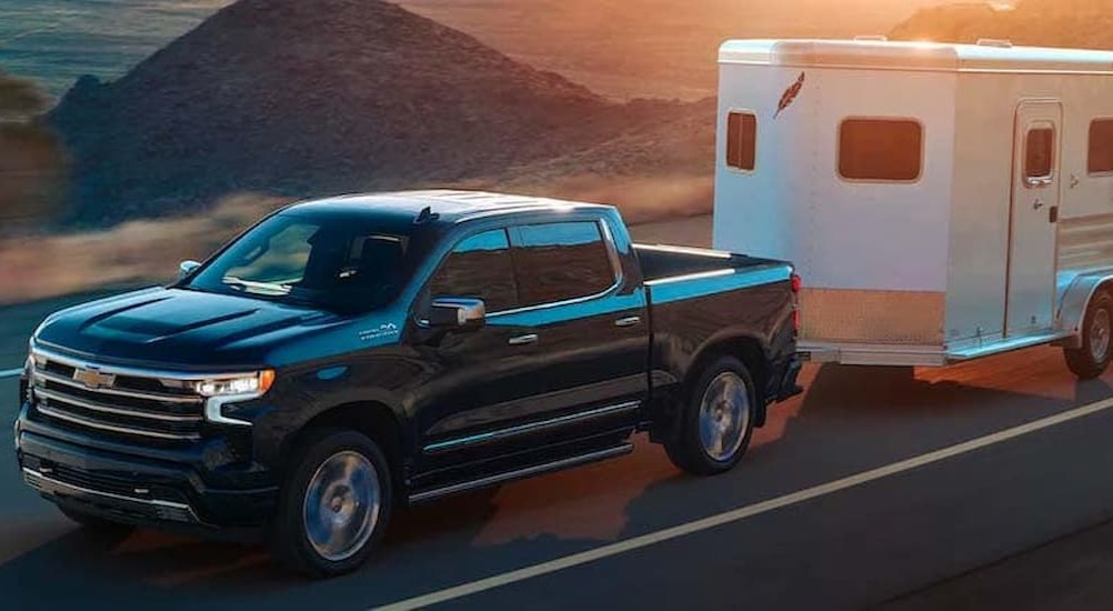 After viewing work trucks near me, a black 2024 Chevy Silverado 1500 High Country, is shown towing a trailer.