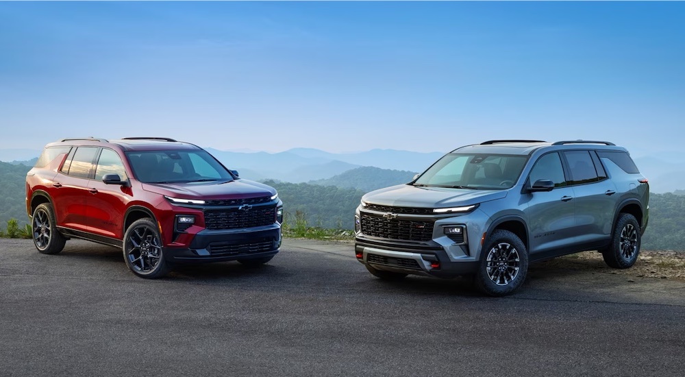 A pair of 2024 Chevy Traverse, one red and the other silver, are shown parked.