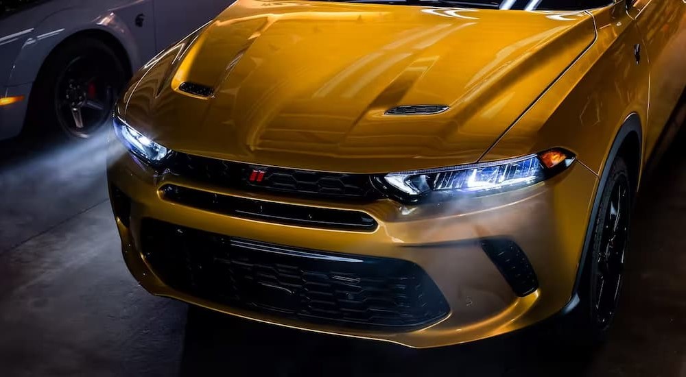 A close-up of the grille and headlights on a yellow 2024 Dodge Hornet are shown.