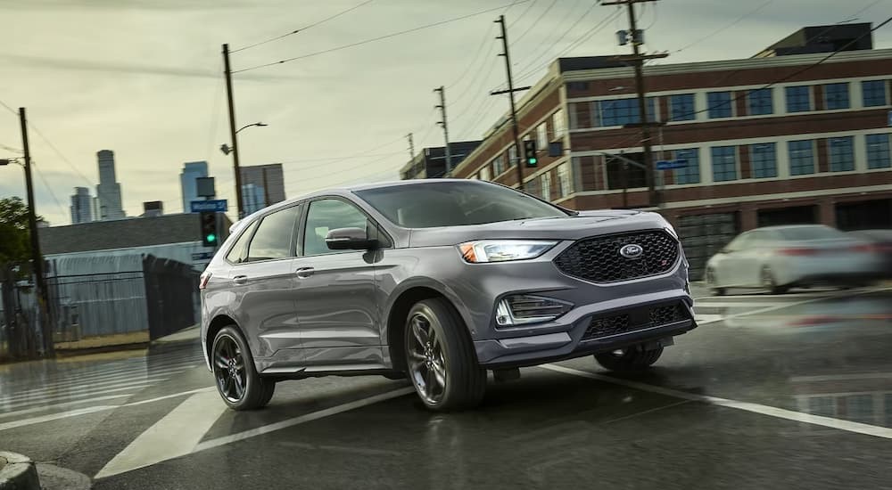 A silver 2024 Ford Edge ST is shown driving on an intersection.