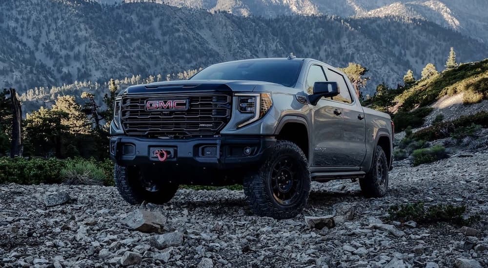 A black 2024 GMC Sierra 1500 is shown parked off-road in the mountains.