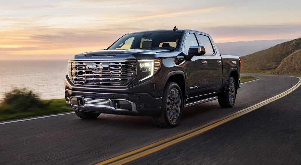 A black 2024 GMC Sierra 1500 is shown driving on the road after winning the 2024 GMC Sierra 1500 vs 2024 Chevy Silverado 1500 contest.