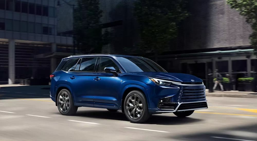 A blue 2024 Lexus TX for sale is shown driving on a city street.