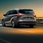 A grey 2024 Toyota Sienna is shown driving away from a Toyota dealer.