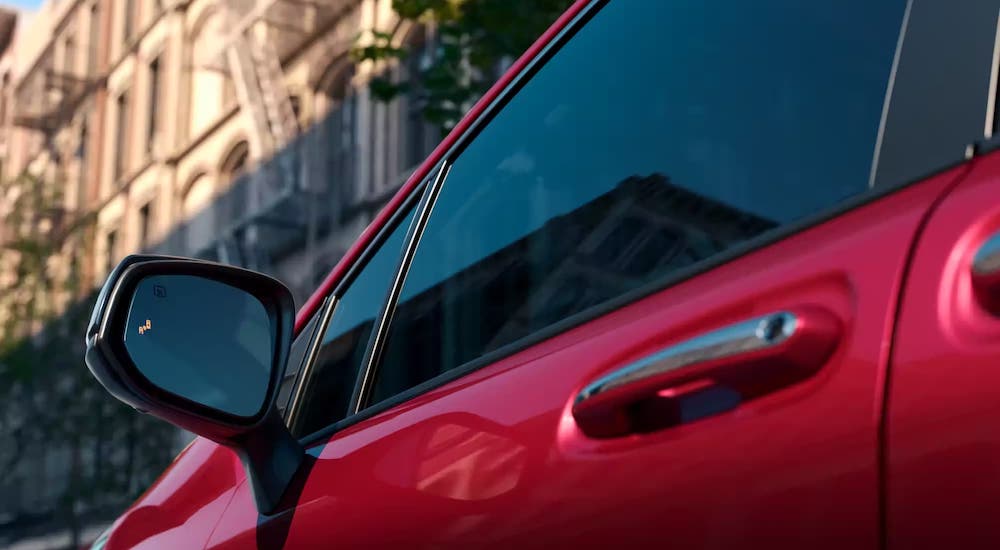 A close-up on the side window of a red 2024 Toyota Sienna is shown.