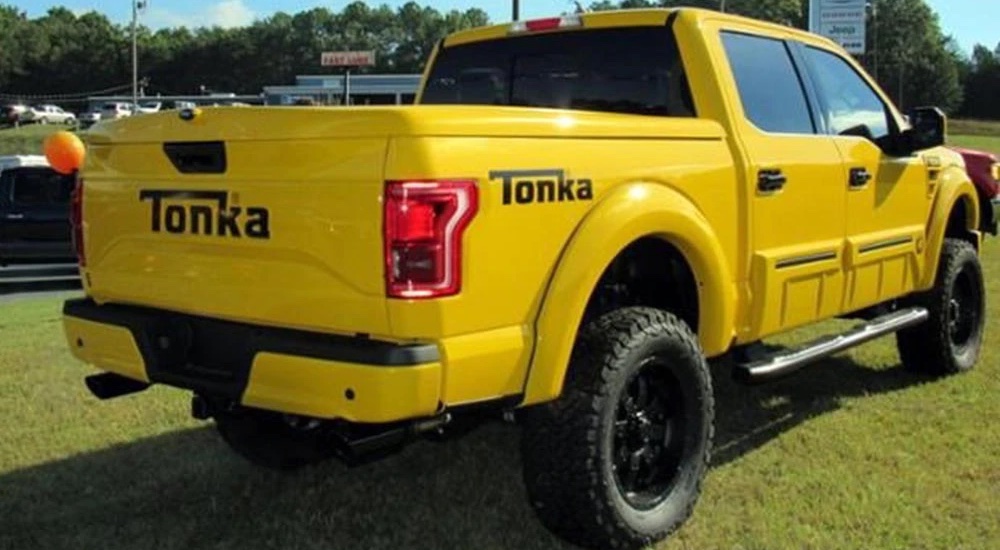 A bright yellow Ford F-150 Tonka is shown parked in a field.