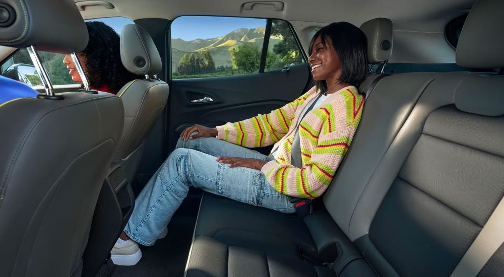 A passenger is shown in the back seat of a 2024 Chevy Trax for sale.