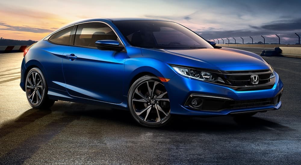 A blue 2020 Honda Civic Coupe Sport is shown parked on a racetrack.