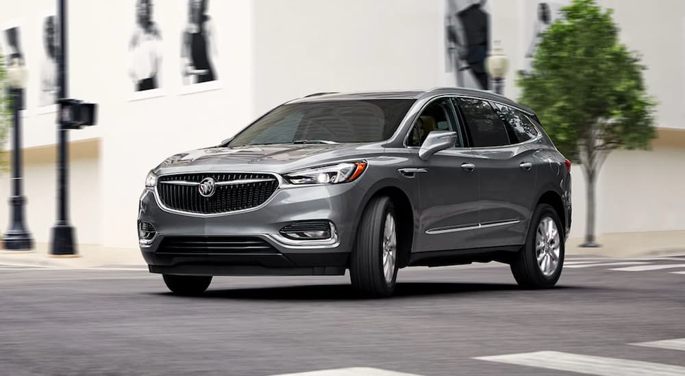 A silver 2021 Buick Enclave is shown driving through a city.