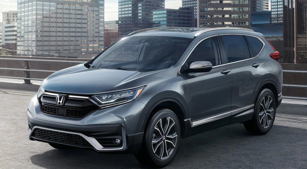 A gray 2021 Honda CR-V is shown parked near city buildings.