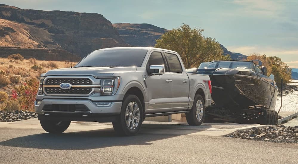 One of the new Ford trucks for sale, a white 2023 Ford Lobo, is shown towing a boat.