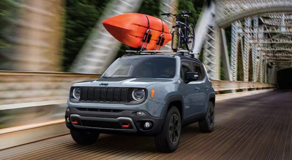 A blue 2023 Jeep Renegade is shown driving on a bridge.