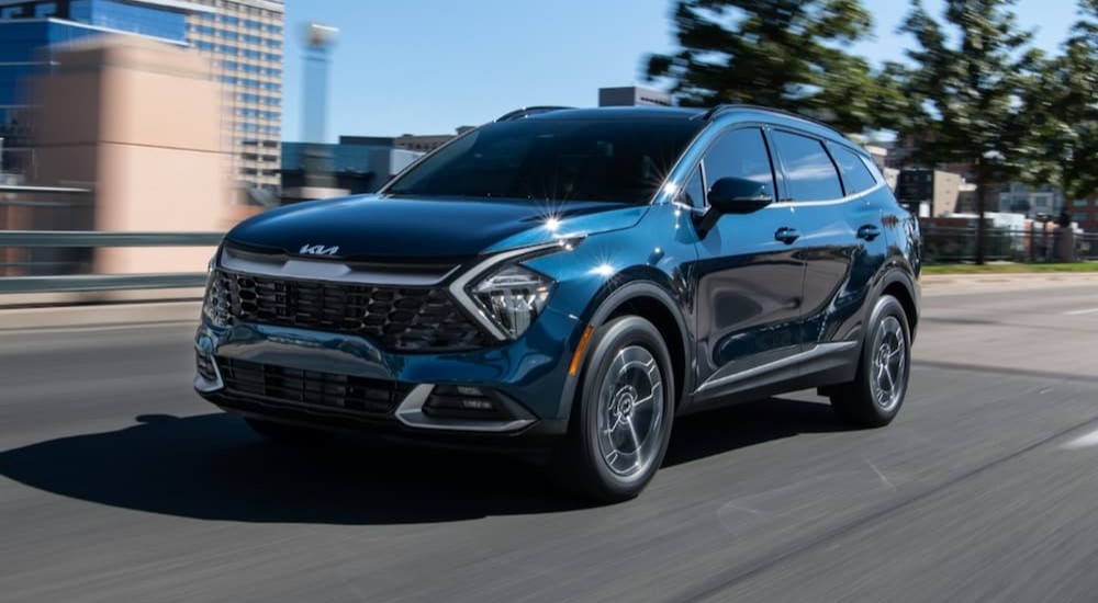 A popular Kia hybrid, a blue 2023 Kia Sportage Hybrid, is shown driving on a city street.