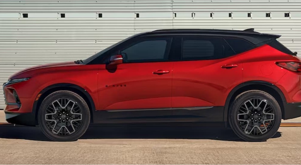 A red and black 2024 Chevy Blazer is shown parked near a garage.