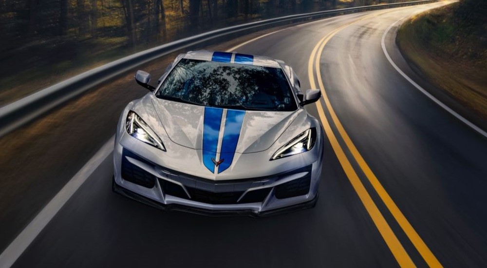 A silver and blue 2024 Chevy Corvette E-Ray 3LZ is shown driving on a highway.