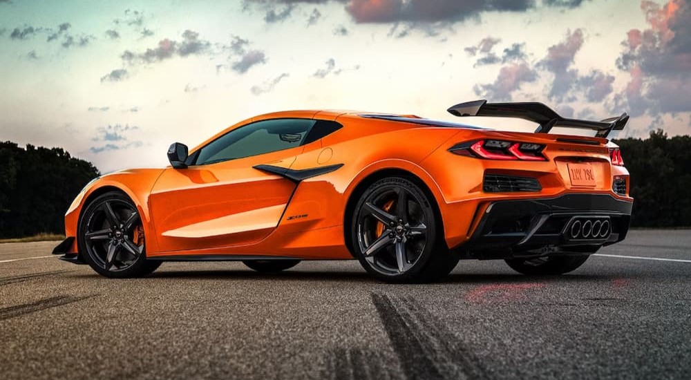 An orange 2024 Chevy Corvette Z06 is shown parked near a Chevy dealer.