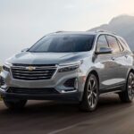 A white 2024 Chevy Equinox EV is shown driving.