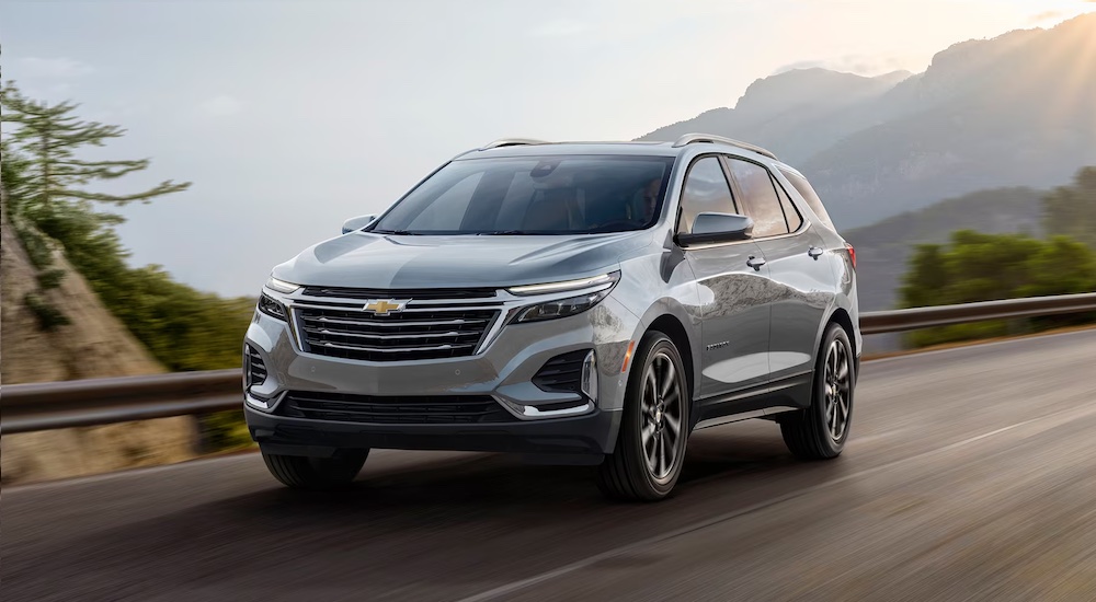 A white 2024 Chevy Equinox EV is shown driving.