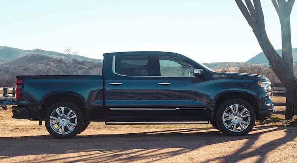 A black 2024 Chevy Silverado 1500 High Country is shown parked near a fence after competing in a 2024 Chevy Silverado 1500 vs 2024 Ford F-150 comparison.