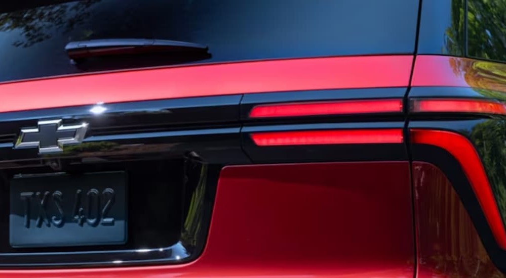 The taillight and badge of a red 2024 Chevy Traverse is shown.