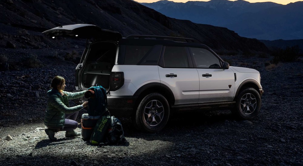 A person loading gear into the back of a white 2024 Ford Bronco Sport Big Bend.