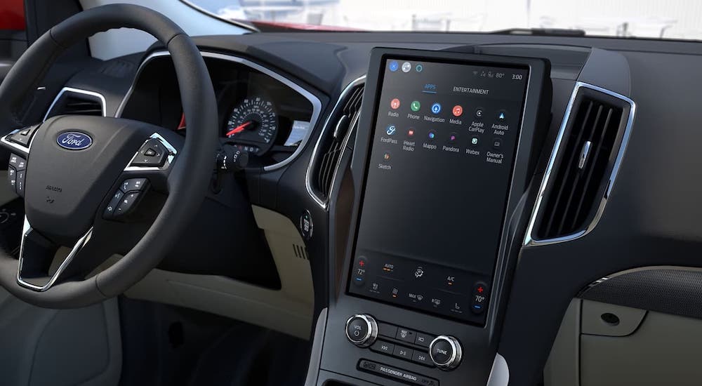 The black interior of a 2024 Ford Edge is shown, including the wheel and dashboard interface.